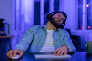 Exhausted man asleep at computer desk at home - obrazy, fototapety, plakaty
