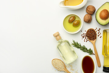 Vegetable fats. Different oils in glass bottles and ingredients on white table, flat lay. Space for...