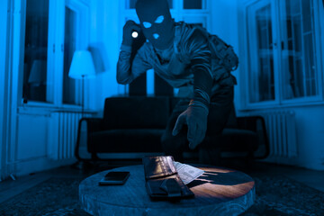 Burglar with flashlight stealing wallet and phone