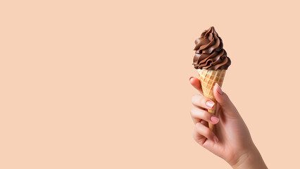 Hand holding a chocolate soft serve ice cream cone against a brown background with copy space