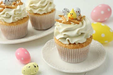 Tasty Easter cupcakes with vanilla cream on white table, closeup