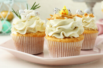 Tasty Easter cupcakes with vanilla cream on light wooden table