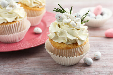 Tasty Easter cupcakes with vanilla cream on wooden table, closeup