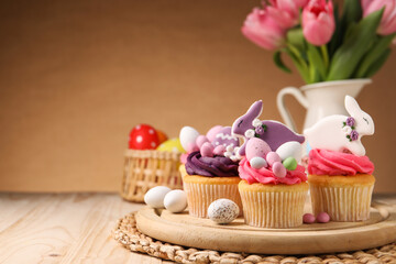Tasty cupcakes with Easter decor on wooden table, space for text