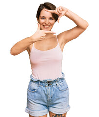 Young brunette woman with short hair wearing casual summer clothes smiling making frame with hands and fingers with happy face. creativity and photography concept.