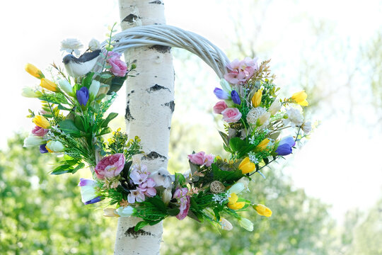 beautiful decorative Spring wreath hanging in garden, natural background. symbol of Beltane holiday. festive decor for spring