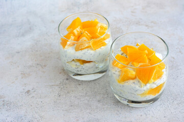 two small glasses of chia pudding with orange pieces  