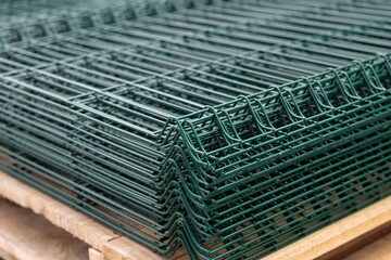 PVC Coated Curvy Welded Fence on warehouse. Building materials. Green sections of wire mesh for...