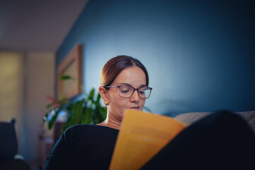 Mujer con lentes leyendo en casa