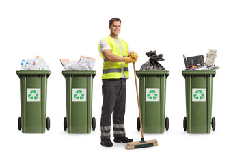 Cleaner in a uniform holding a broom in front of recycling bins