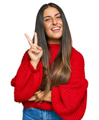 Beautiful hispanic woman wearing casual clothes smiling with happy face winking at the camera doing victory sign with fingers. number two.