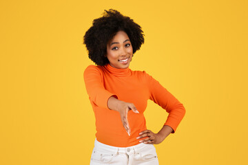 Smiling woman with afro hair in orange turtleneck offering a handshake