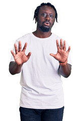 Young african american man with braids wearing casual white tshirt moving away hands palms showing refusal and denial with afraid and disgusting expression. stop and forbidden.