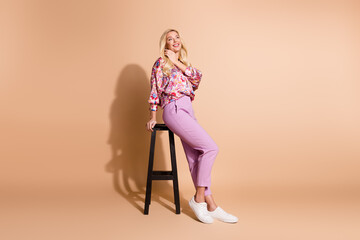 Full body portrait of pretty lady sit stool empty space wear shirt isolated on beige color...