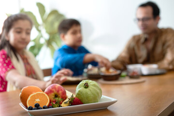 Happy Indian family in traditional cloth, father daughter and son chatting happily over meal, family enjoying tasting Indian food, selective focus