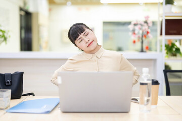 White-collar worker sitting on an office chair and turning his neck to move his body