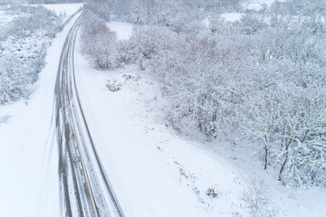 drone aerial view of a road in a snow-covered landscape, concept of winter time transportation