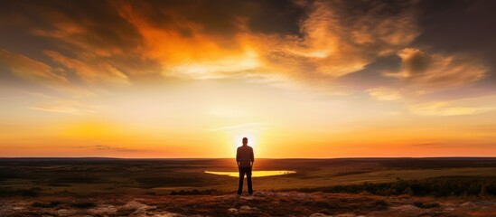 Natural sunset landscape with man standing looking silhouette sky - obrazy, fototapety, plakaty