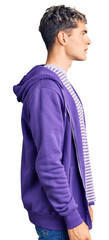 Young handsome man wearing casual purple sweatshirt looking to side, relax profile pose with...