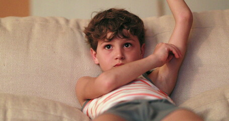 Young boy seated in living-room sofa watching TV screen