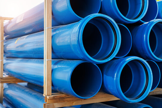 Close-up blue PVC plumbing pipes stacked wooden pallets replacement at german city street infrastructure construction site. Town development building industrial background