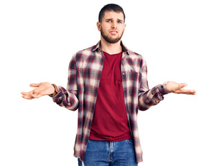 Young handsome man wearing casual shirt clueless and confused with open arms, no idea concept.