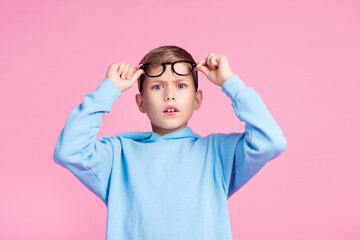Portrait of impressed speechless boy hands touch eyeglasses staring isolated on pink color background - obrazy, fototapety, plakaty