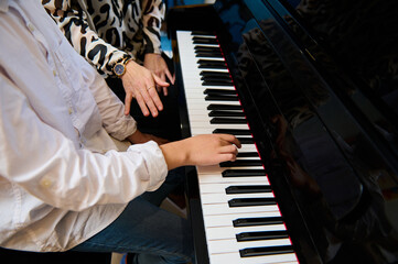 Selective focus to teenage boy musician pianist fingers and piano key to play the piano. Close-up...