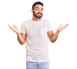 Young hispanic man wearing casual clothes clueless and confused expression with arms and hands raised. doubt concept.