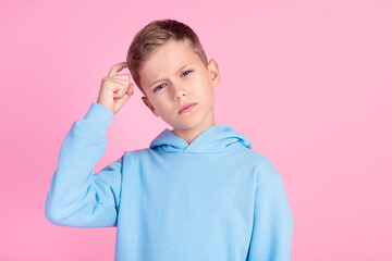Portrait of minded boy hand finger scratch head contemplate empty space isolated on pink color...