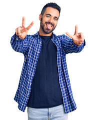 Young hispanic man wearing casual clothes smiling with tongue out showing fingers of both hands...