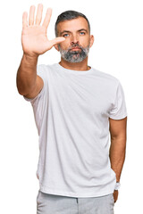 Middle age handsome man wearing casual white tshirt doing stop sing with palm of the hand. warning...