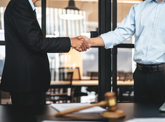 Handshake after good cooperation, Two people shaking hands after discussing contract agreement on front a judge's gavel - 775183848