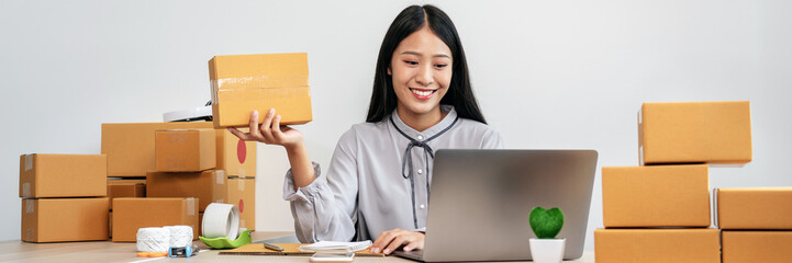 Young woman small business entrepreneur working at home recieve ordering from online customer and checking data while preparing to packing product deliver sending to client - 775185216