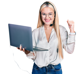 Beautiful blonde woman working with laptop wearing operator headset screaming proud, celebrating victory and success very excited with raised arms