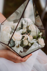 The image shows a hand holding a bouquet of white flowers, possibly roses, in an indoor setting 6899.