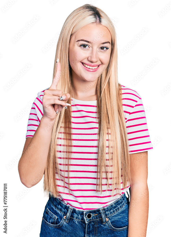 Wall mural beautiful blonde woman wearing casual striped t shirt showing and pointing up with finger number one