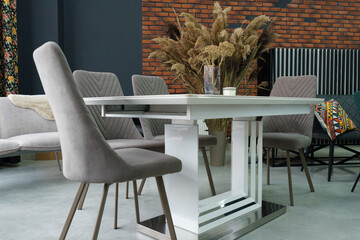White wooden table combined with gray wooden chairs with soft fabric upholstery. There is a black...