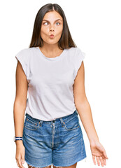 Obraz premium Young caucasian woman wearing casual white tshirt making fish face with lips, crazy and comical gesture. funny expression.