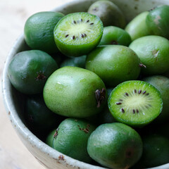 Kiwi berries (hardy kiwi) in a bowl, with fruit cross-sections shown