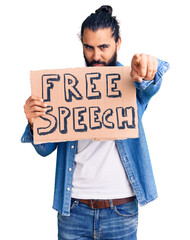 Young arab man holding free speech banner pointing with finger to the camera and to you, confident gesture looking serious