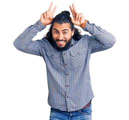 Young arab man wearing casual clothes posing funny and crazy with fingers on head as bunny ears, smiling cheerful