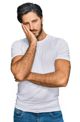 Young hispanic man wearing casual white t shirt thinking looking tired and bored with depression problems with crossed arms.