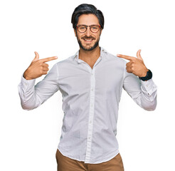 Young hispanic man wearing business shirt and glasses smiling cheerful showing and pointing with fingers teeth and mouth. dental health concept.