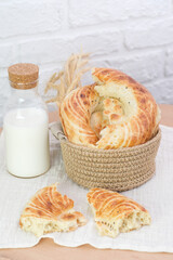 Asian flatbread in a basket with milk on wooden table on white bricks background, top view.