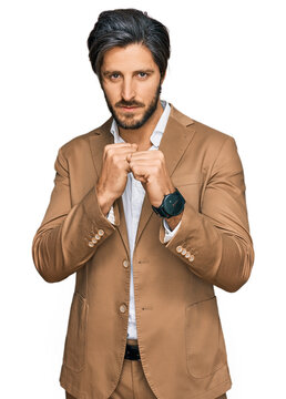 Young hispanic man wearing business clothes ready to fight with fist defense gesture, angry and upset face, afraid of problem
