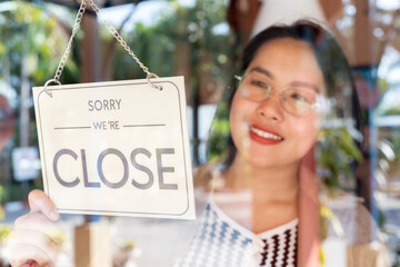 Woman putting closed sign on door of coffee shop.