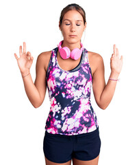 Young beautiful hispanic woman wearing gym clothes and using headphones relax and smiling with eyes closed doing meditation gesture with fingers. yoga concept.