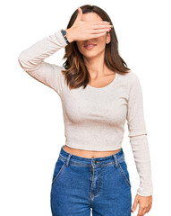 Young brunette woman wearing casual clothes and glasses smiling and laughing with hand on face covering eyes for surprise. blind concept.