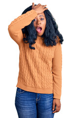 Beautiful african american woman wearing casual  sweater surprised with hand on head for mistake, remember error. forgot, bad memory concept.